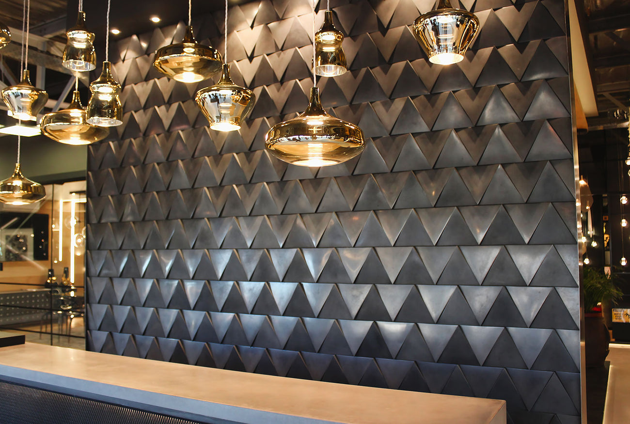 Modern interior with 3D geometric concrete wall tiles and luxury gold pendant lighting, creating a bold and sophisticated design statement.