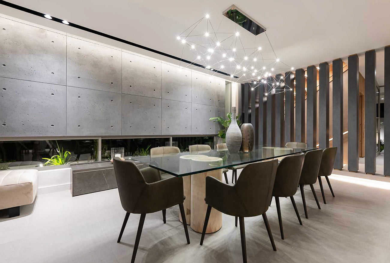 Modern dining room with textured concrete wall panels, glass dining table, and artistic chandelier, creating a sleek and contemporary interior design.