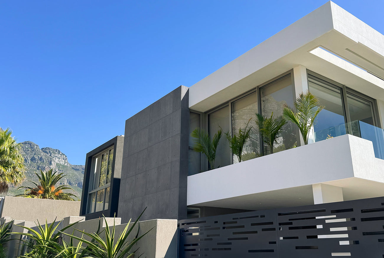 Modern luxury home with silica-free concrete wall panels, large glass windows, and a sleek minimalist design, set against a scenic mountain backdrop.