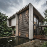 Modern architectural house with textured wall and glass windows, surrounded by greenery. - FLOAT concrete