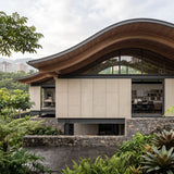 Contemporary architecture and landscape design institute in Medellín, Colombia, featuring FLOAT KONKRETE XXL lightweight concrete wall paneling, a sweeping curved timber roof, floor-to-ceiling glazing and lush tropical landscaping.