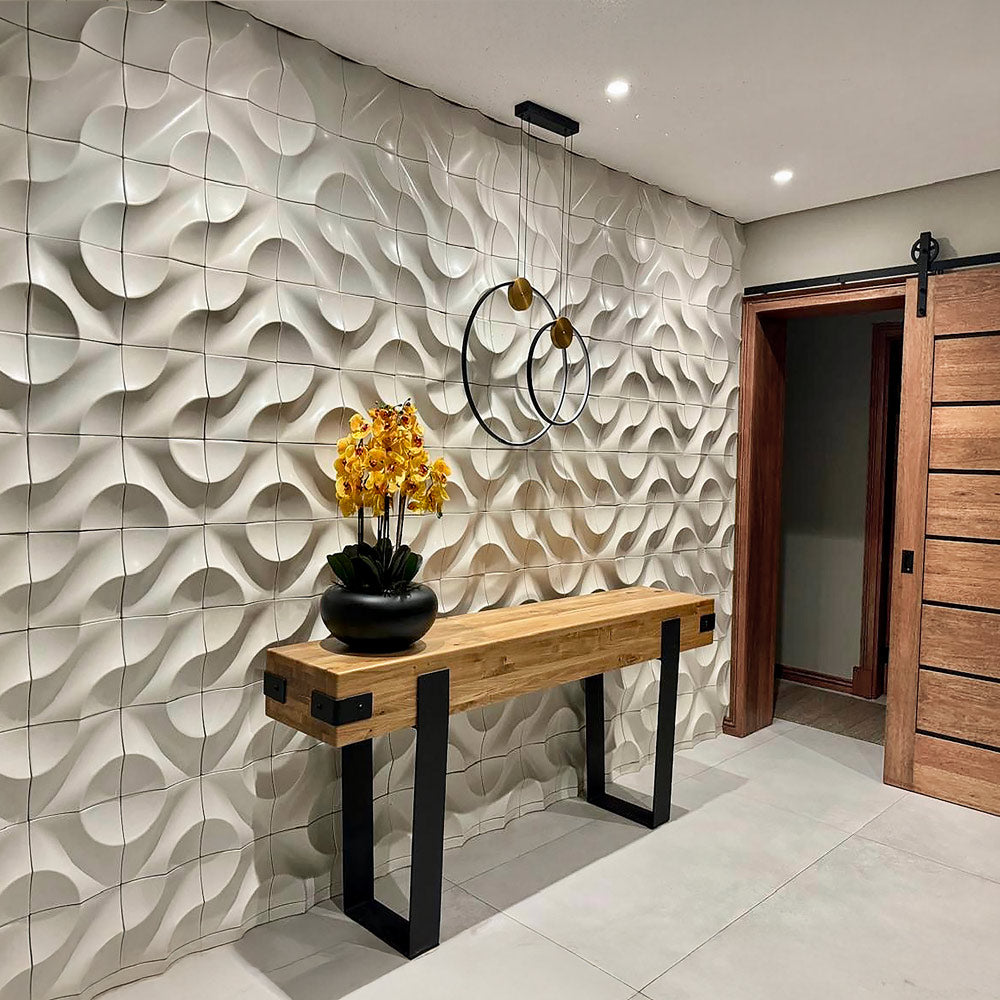 Modern entryway featuring a decorative 3D wall with wavy pattern cladding, a wooden console table with black metal legs, and a vase of yellow orchids under elegant pendant lighting