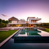 Modern luxury estate house with large glass walls and a rectangular infinity pool reflecting the purple sky at dusk. - FLOAT concrete