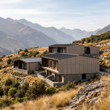 Modern multi-level lodge building in new zealand with wall concrete panels DUNE colour and stone bases, situated on a grassy mountainside with rugged peaks in the background. - FLOAT concrete
